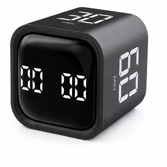 A black cube-shaped digital alarm clock with white LED seven-segment displays showing '00' on the front and '6:01' on the side, photographed on a clean white background.